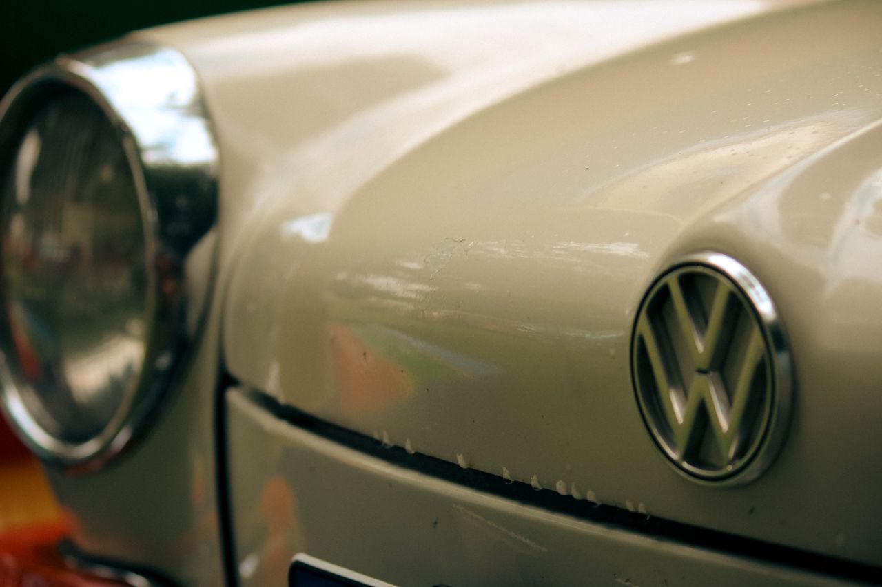 Detailed close-up shot of a vintage Volkswagen Beetle, highlighting the emblem and headlight.